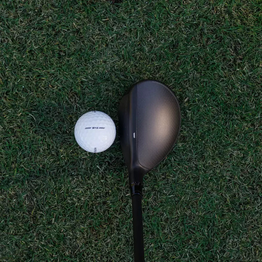 Golfeur homme frappant un hybride de golf depuis le fairway
